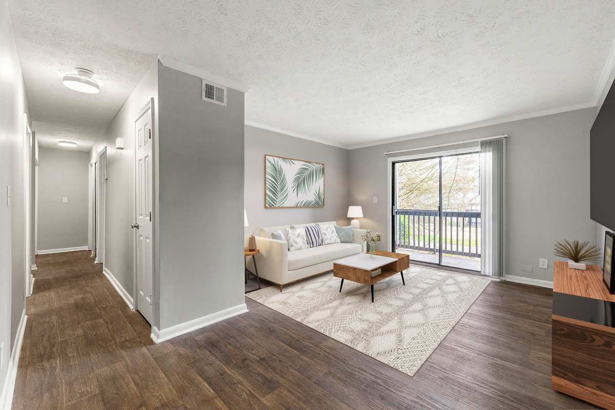 Spacious living room with large couch, coffee table. wood-style flooring and access to private patio at Fields at Peachtree Corners in Norcross, Georgia