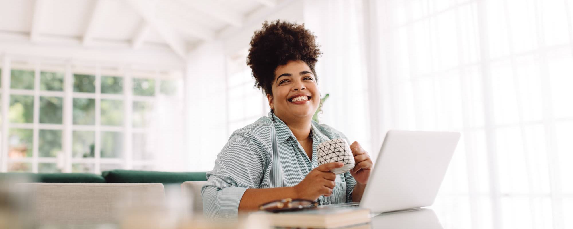 Schedule a Tour | A woman smiling as she works on her laptop at The Lido Apartments in Los Angeles, California