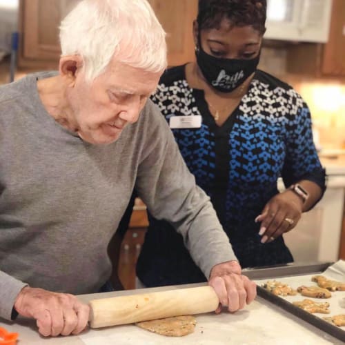 Resident cooking with help from a caretaker at Oxford Glen Memory Care at Sachse in Sachse, Texas