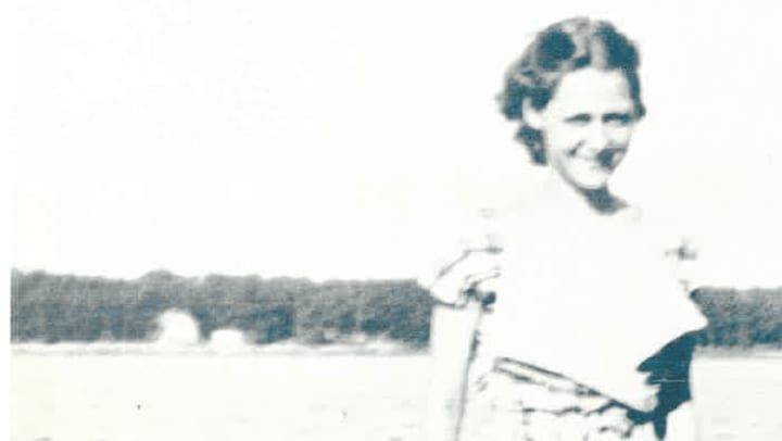 Antique photo of Jean Ray as a young lady standing on the shore of the lake behind her