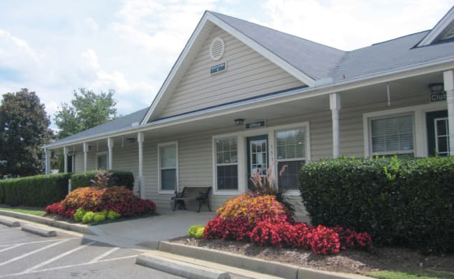 Clubhouse exterior surrounded by flower beds at Station 153 Apartment Homes in Anderson, South Carolina