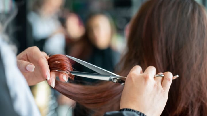 A hair stylist trims a woman’s hair at a South Jordan salon