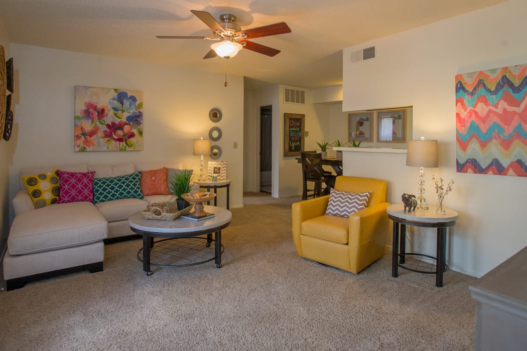 Living room with a ceiling fan and bright decor at Cimarron Trails Apartments in Norman, Oklahoma