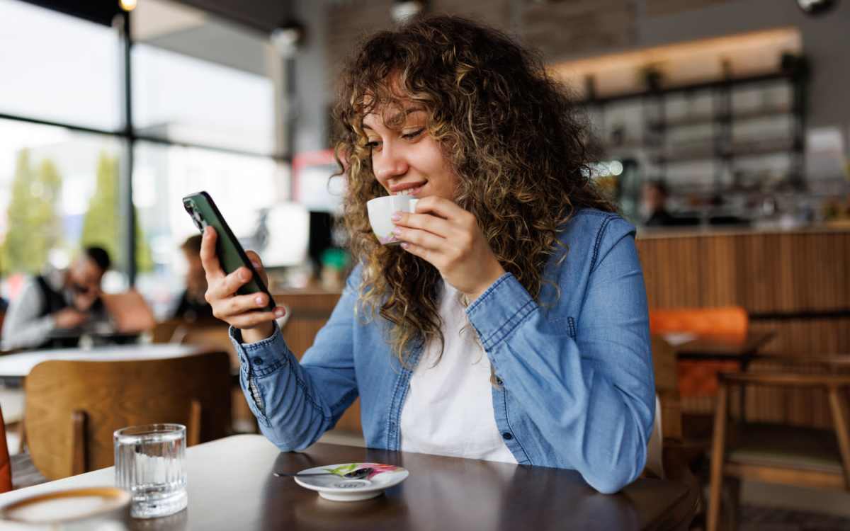 Resident using mobile while enjoying a cup of coffee in favorite cafe near Renton Sage in Renton, Washington
