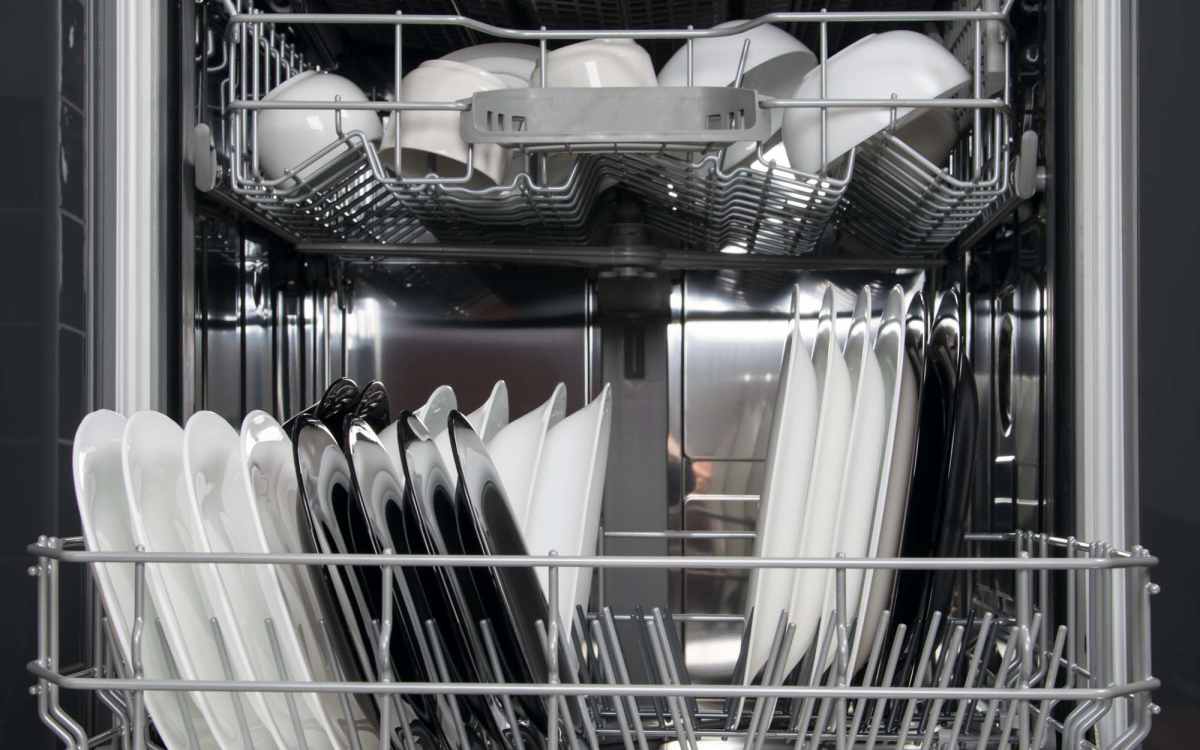 Dishwasher loaded with clean white and black plates at Mosaico Family Housing in Burien, Washington