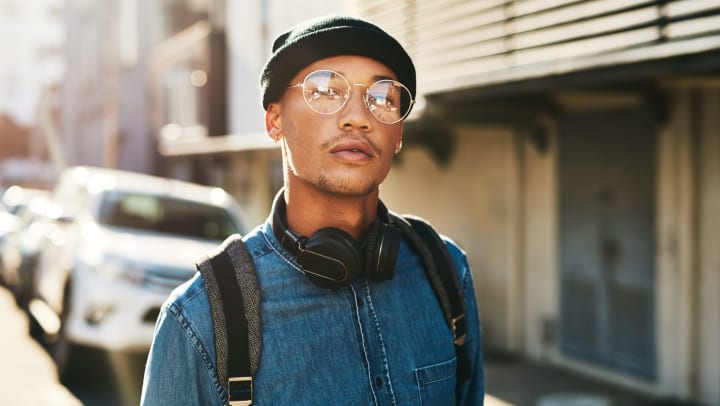 Man wearing black beanie with matching headphones and backpack straps.