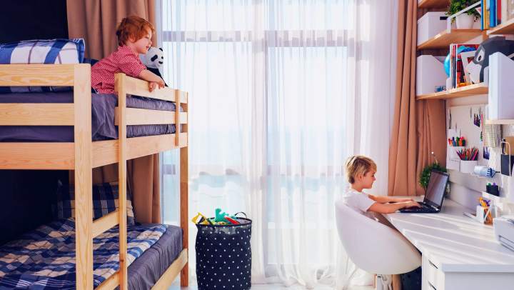 Two kids sharing a bedroom with a bunk bed and desk 