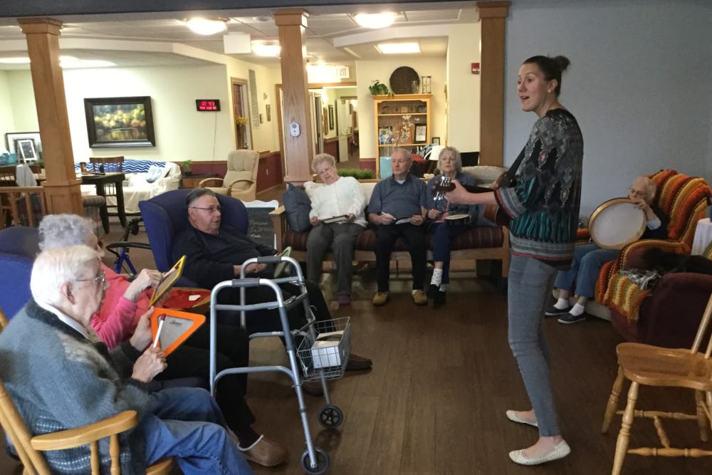 Staff member with residents playing the guitar at Prairie Hills Independence in Independence, Iowa.