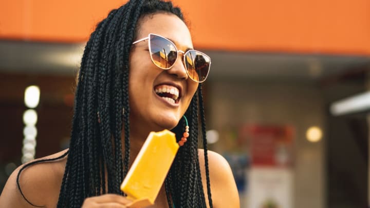 A woman laughing and holding a popsicle from an ice cream shop in Jacksonville.