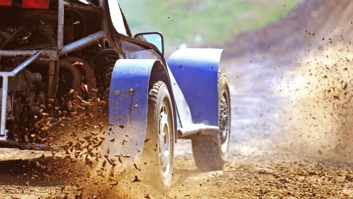 Close up of a blue car racing on a dirt track