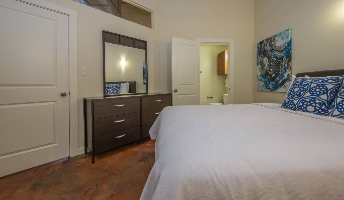 Bedroom with comfortable bed and bed lamp at District Square Apartments in Richmond, Virginia