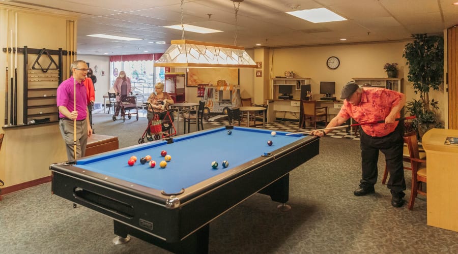 Independent living resident playing billiards with his son in the clubhouse at Cascade Park Vista Assisted Living in Tacoma, Washington
