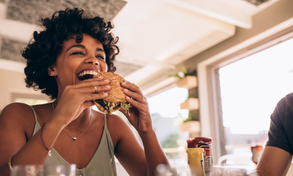 Resident diving into a freshly made burger at her favorite restaurant near Parkwood in Lancaster, California