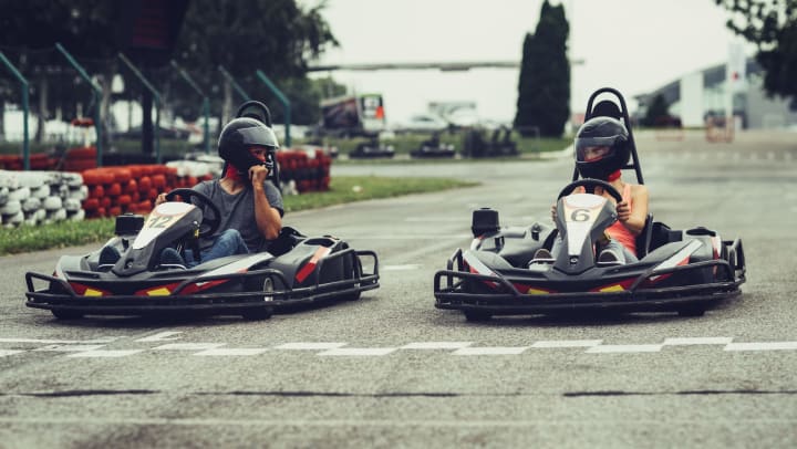 Two people on go-karts from start position on race track.