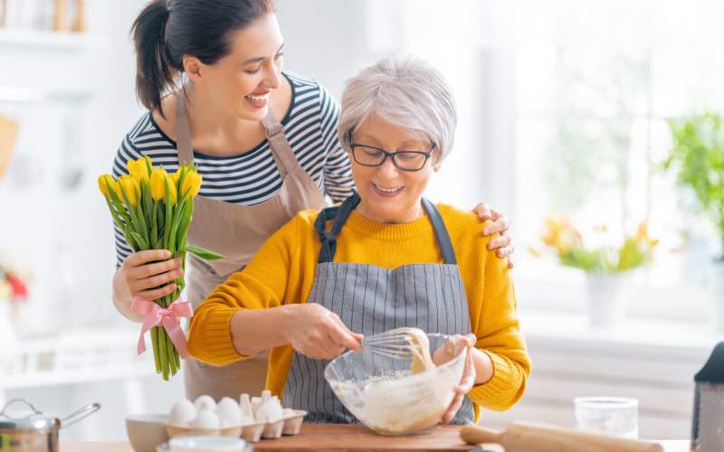 Happy resident mixing dough with her daughter at The Pineapple House at Sapphire Lakes in Naples, Florida