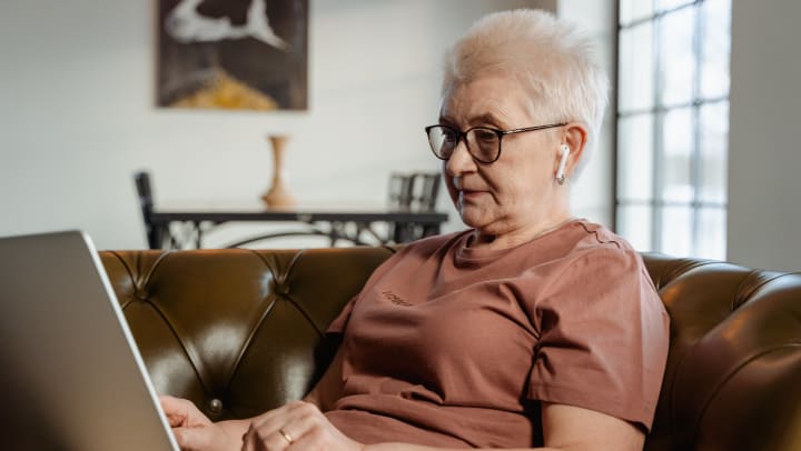 Elderly woman using a laptop on a couch