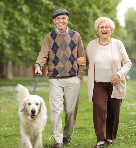 Senior couple taking a dog fo a walk at Kenmore Senior Living in Kenmore, Washington