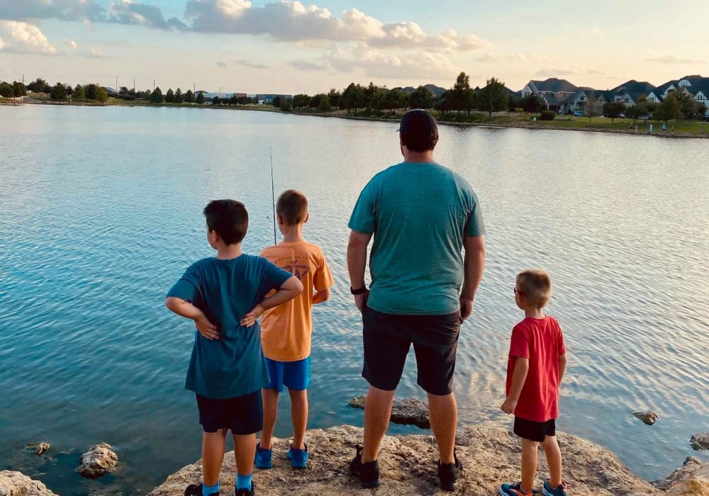 Father and three boys fishing on the edge of the pond at BB Living Harvest in Argyle, Texas