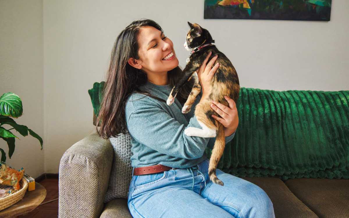 Woman sitting on a couch playing with her cat at Carrara At Cole in Dallas, Texas