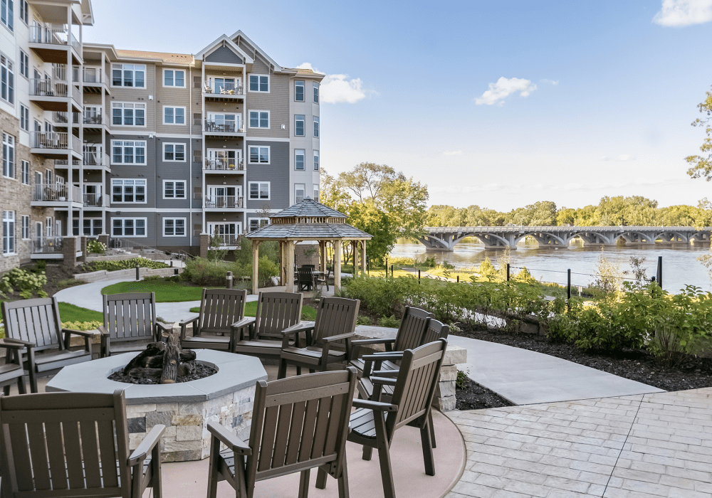 Patio lounge and fire pit area overlooking the nearby lake at an Applewood Pointe Cooperative Communities property