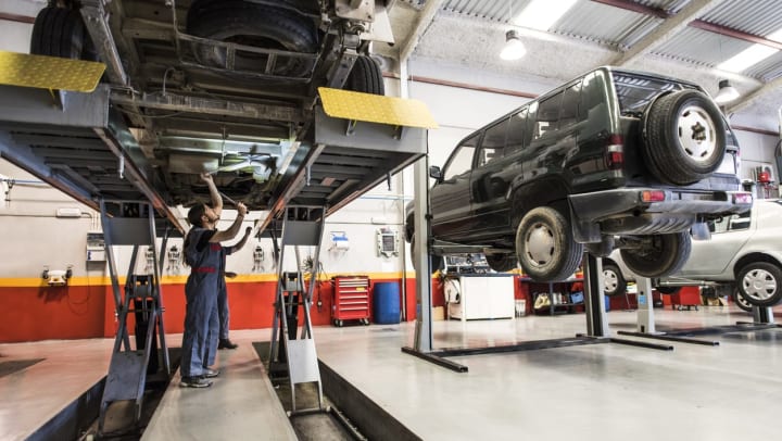 mechanic working underneath car on a car elevator