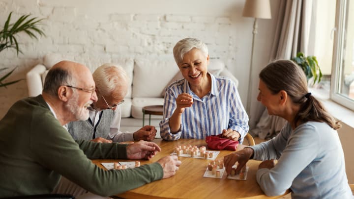 Group of elderly people around a table with game chips and smiles on their faces. 