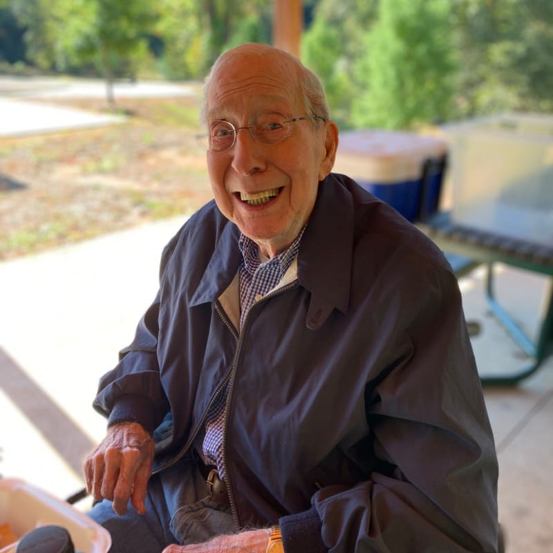 Resident smiling and enjoying a picnic at the outdoor patio at The Foothills Retirement Community in Easley, South Carolina