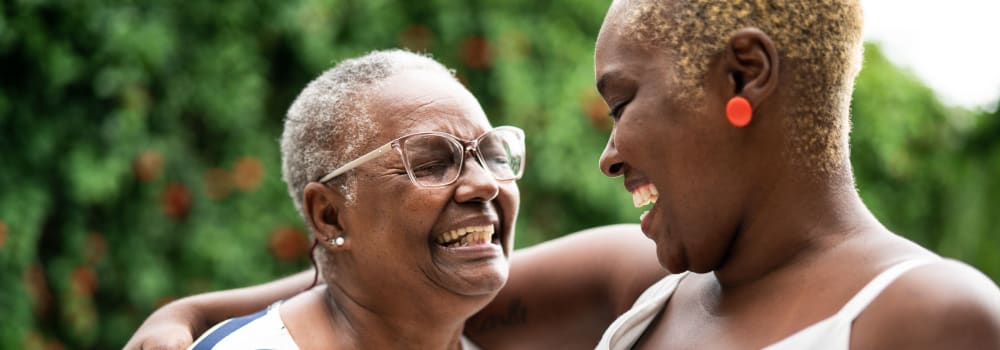 A young person putting their arm around a resident at a Stoney Brook community. 