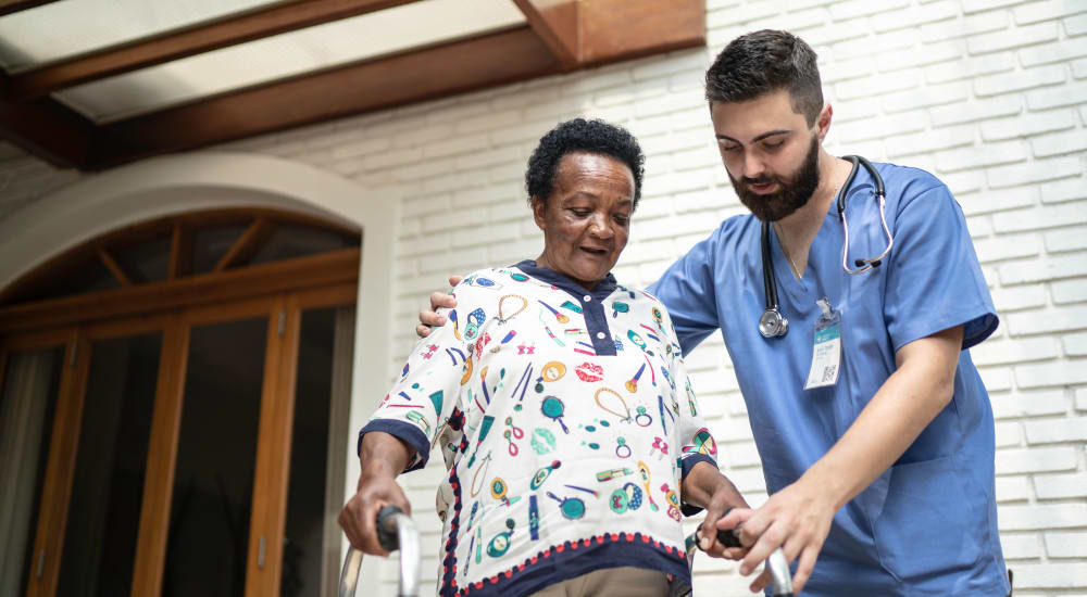 A staff member helping a resident walk outside at The Lakes at Banning in Banning, California. 