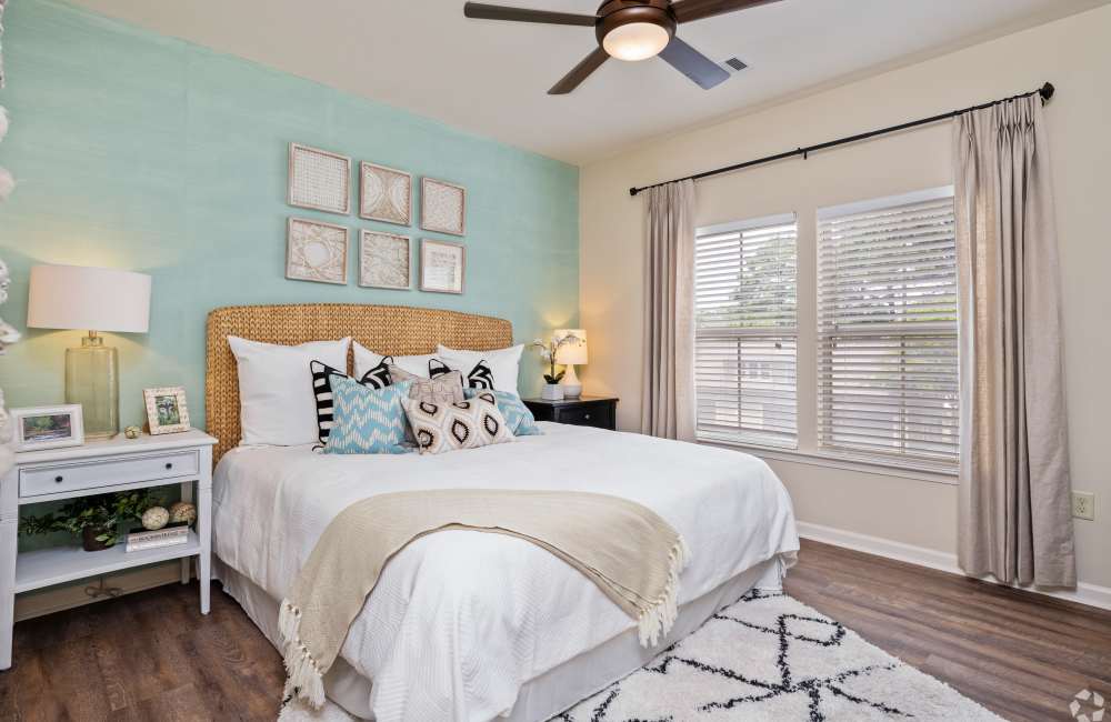 Spacious bedroom with a comfortable bed, ceiling fan and a large sliding window at The Park Apartment Homes in Prattville, Alabama