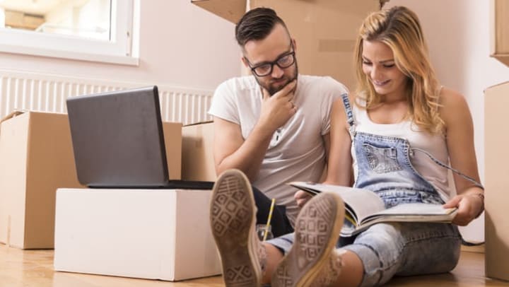 Woman and man surrounded by boxes sitting on floor.