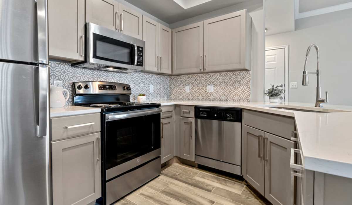 Modern kitchen with stainless-steel appliances and wood-style flooring at Charleston in San Antonio, Texas