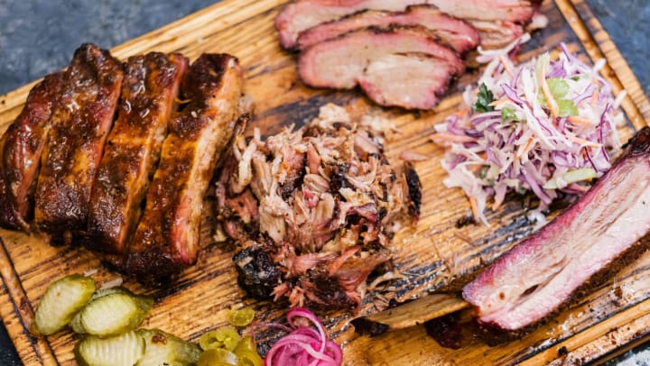 An assortment of smoked meat on a wooden board | BBQ restaurants in Savannah