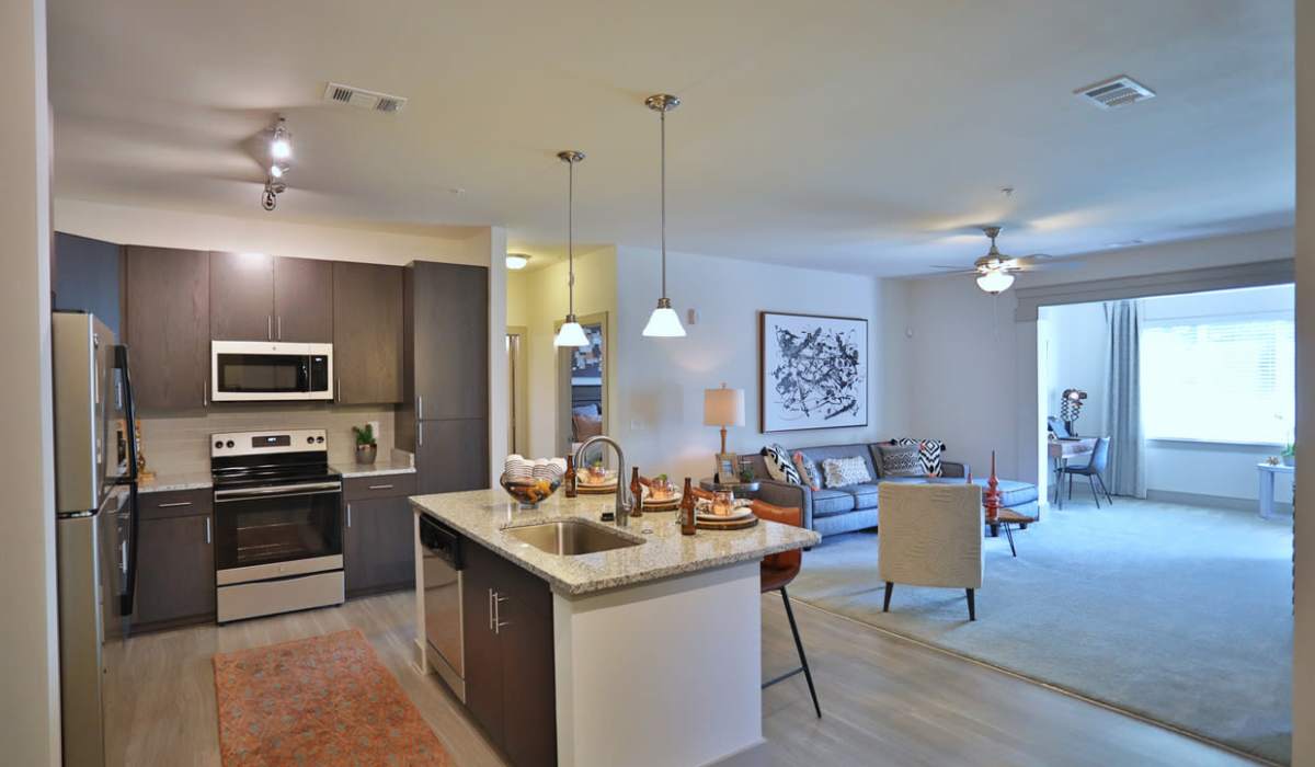 Modern kitchen with granite countertops, stainless steel appliances, and open layout living area with wood-style flooring at Haven at Rivergate in Charlotte, North Carolina