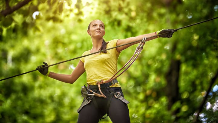 Woman in adventure park with her hands on ropes