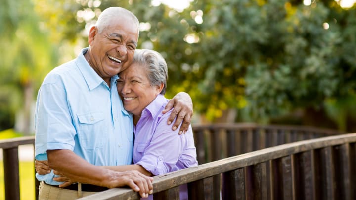 Senior couple hugging and smiling on bridge