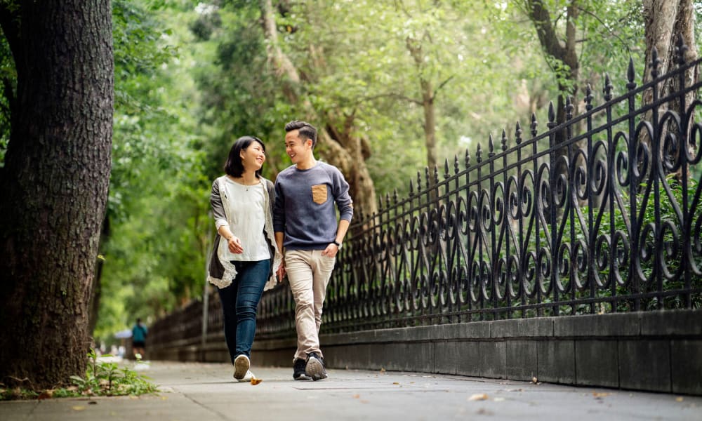 Resident couple conversing while strolling through a tree-lined park near Oaks White Rock in Dallas, Texas