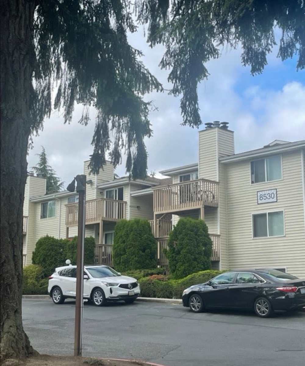 View of exterior of apartments and green lawn at Amber Glen Apartments in Everett, Washington