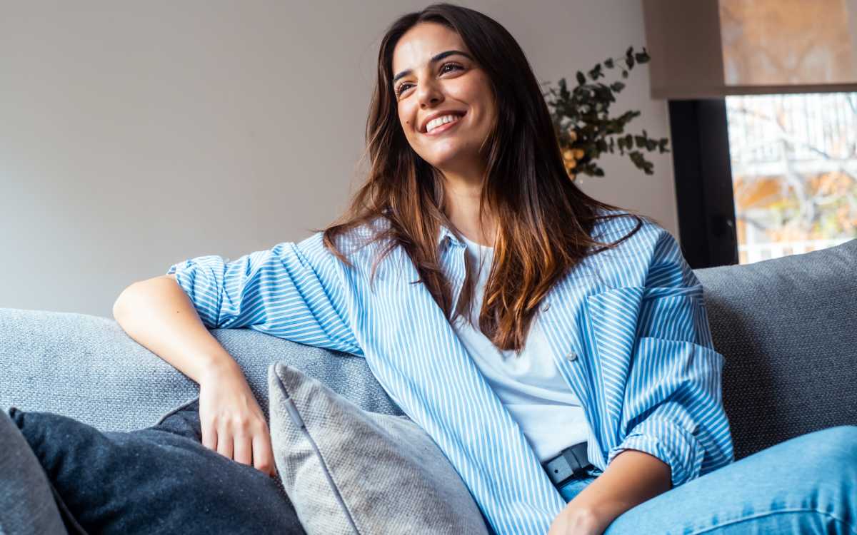 Woman smiling on a gray couch with pillows at 36 Palms Townhomes in Missouri City, Texas 