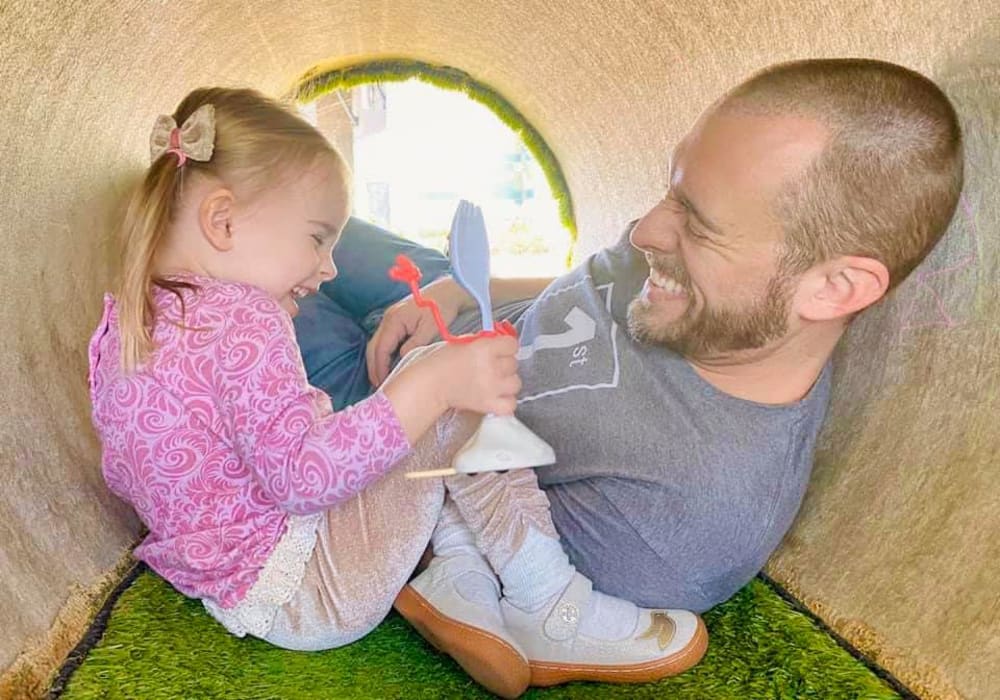 Father and daughter playin gin tunnel at playground BB Living Harvest in Argyle, Texas