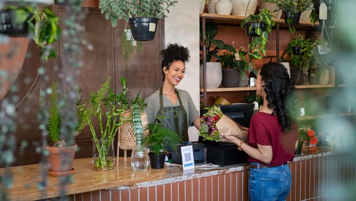 Smiling woman standing behind a counter selling plants | florists near Irvine