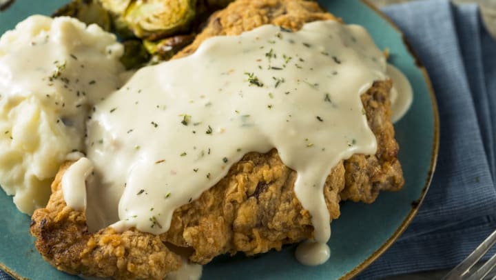 A close-up of homemade, country-fried steak covered in cream gravy with mashed potatoes | Brunswick restaurants