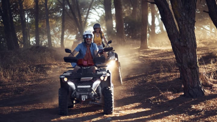 Two people riding ATVs in the forest