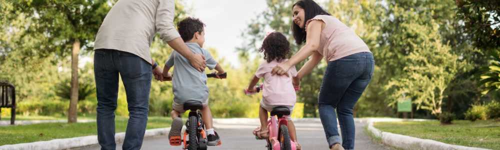 Parents helping their children riding a bike at a park near Encore at West Valley in White Lake, Michigan