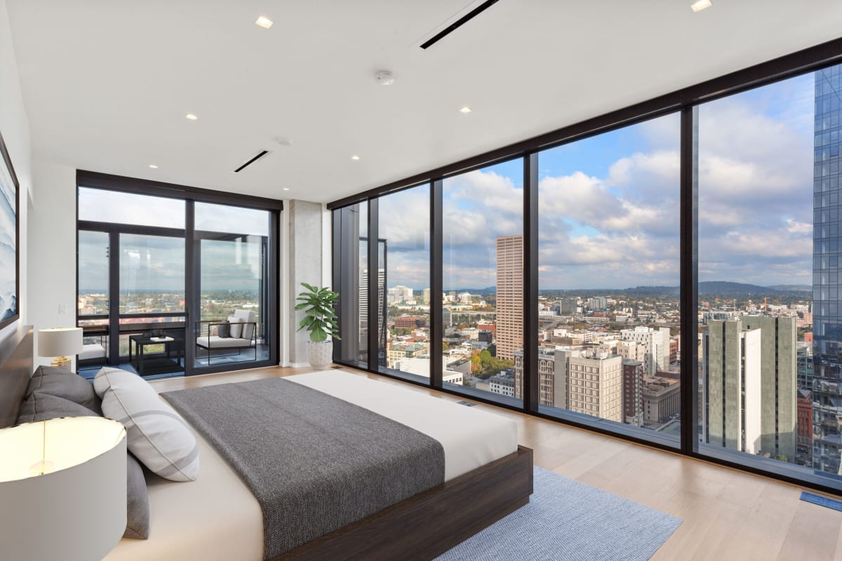 Bedroom with large windows overlooking the city at The Residences at 11W in Portland, Oregon
