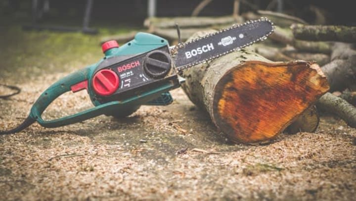 chain saw not in use leaned up against log | Photo by Sven Brandsma on Unsplash