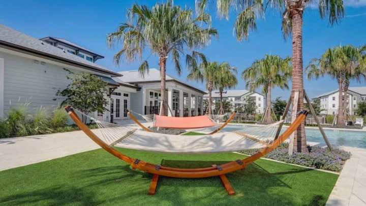 Two free-standing hammocks on green grass underneath palm trees