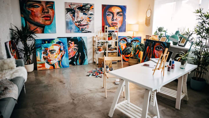 An art studio with paintings on the wall and many art supplies