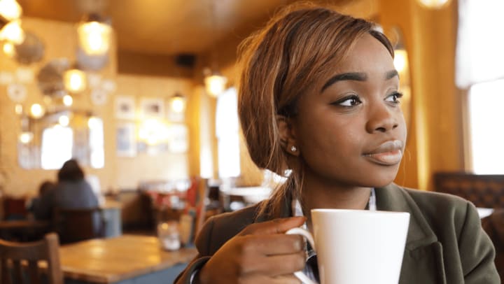 Young woman holding coffee mug in a coffee shop