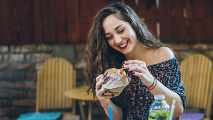 Woman eating a wrap at an outside table